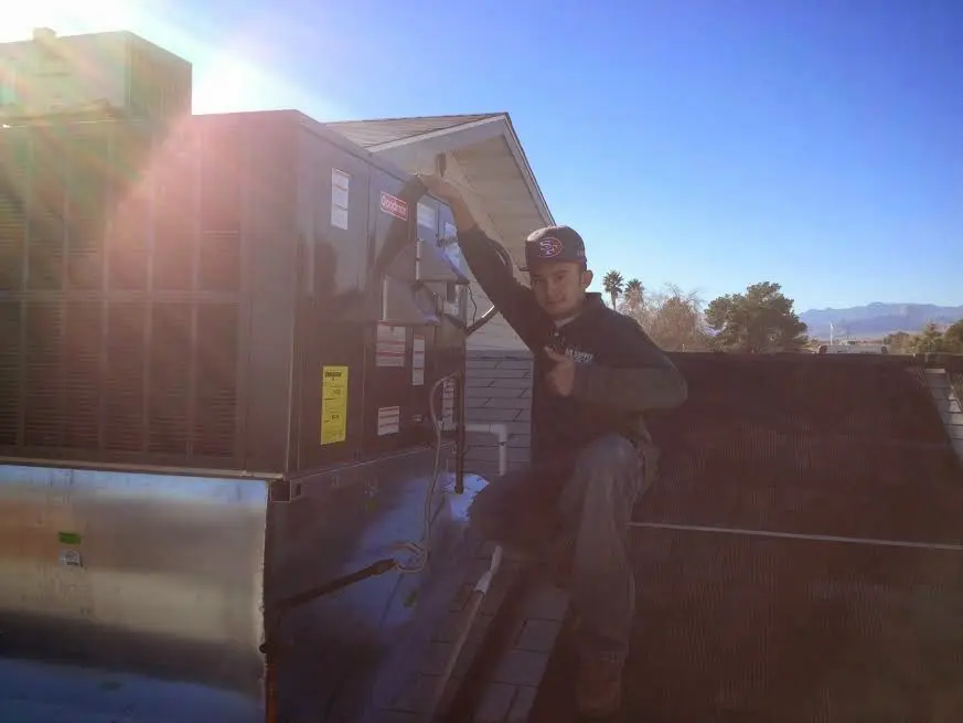 HVAC technician performing Air Duct Cleaning on a rooftop unit in Waterloo